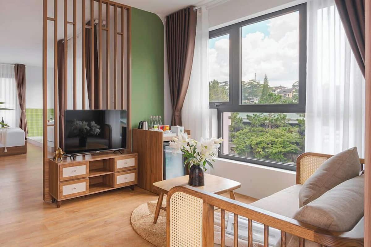 A modern living room with a TV, wooden furniture, a dining area, and a large window with a view.