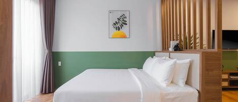 A hotel room with a bed, a green accent wall, a wooden partition, and a framed artwork.