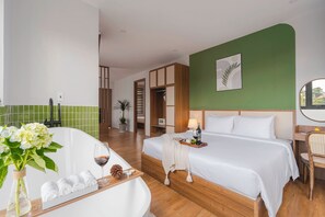 A hotel room with a bed, a desk, a chair, a vanity with a mirror, a green wall, and a potted plant. - Nature Hotel - Le Hong Phong (Da Lat)