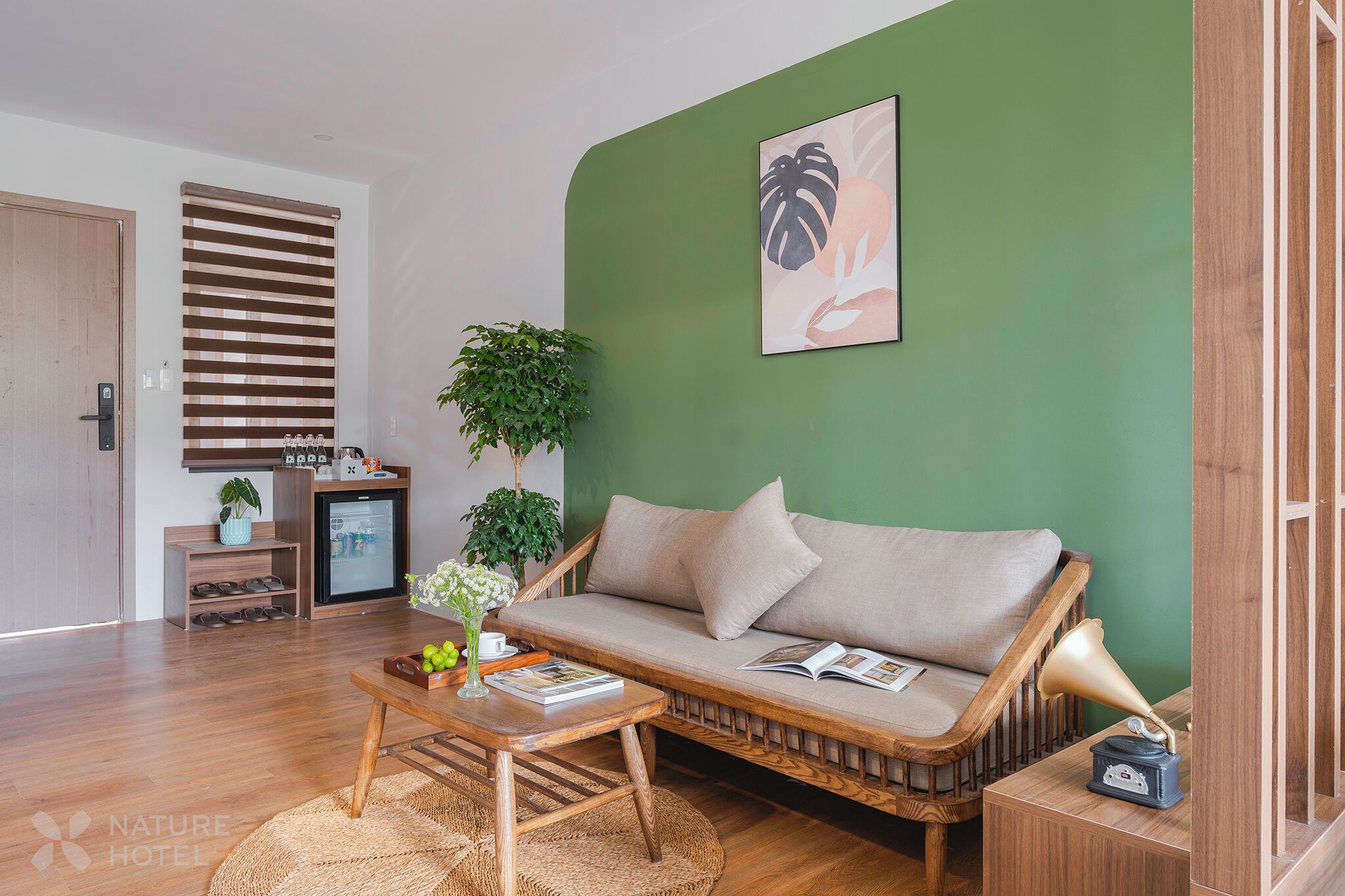 A modern living room with a green accent wall, a sofa, a coffee table, and a small side table with a lamp.