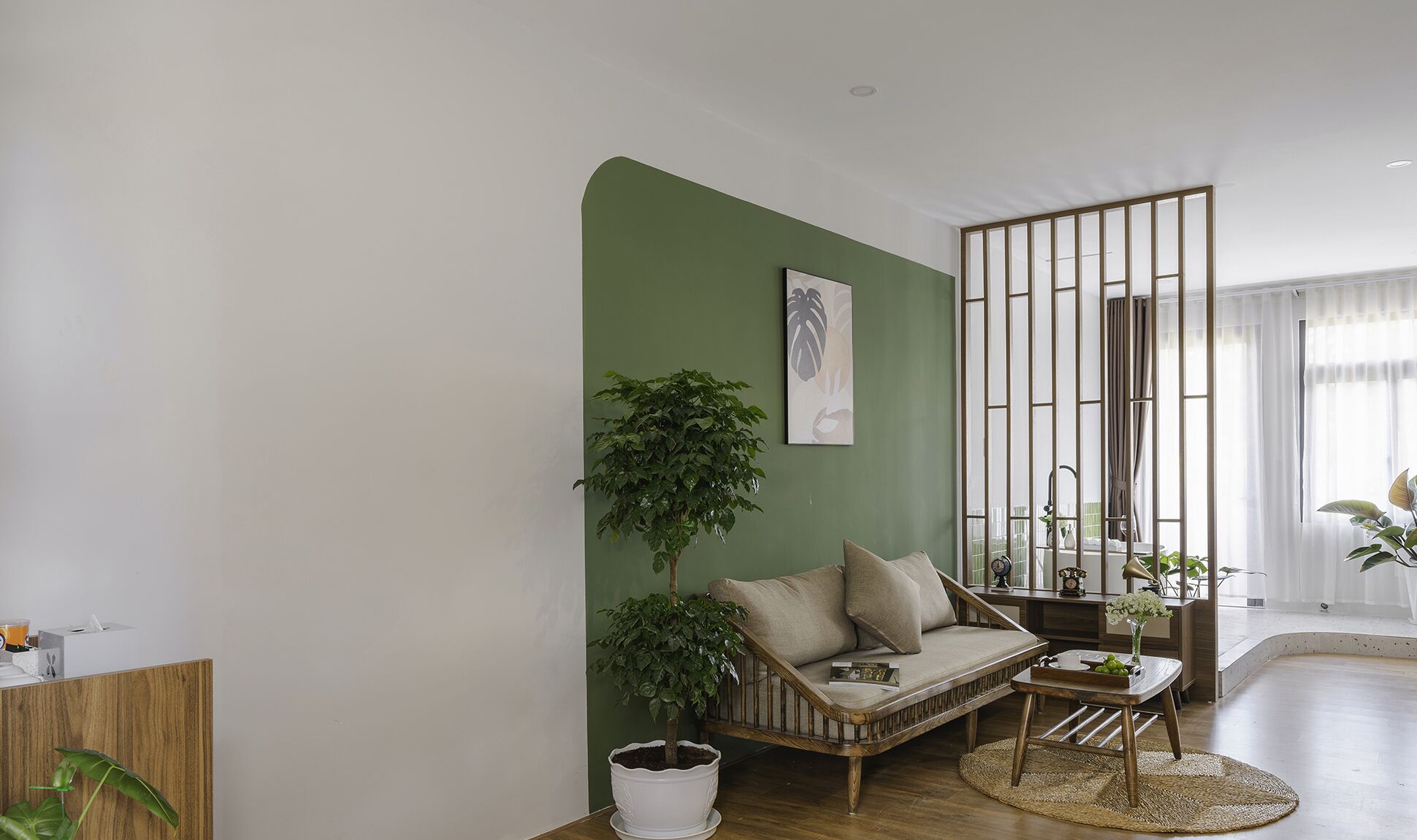 A living room with a green accent wall, a sofa, a coffee table, and a potted plant.