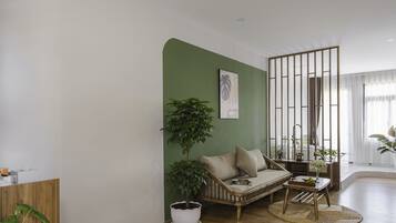 A living room with a green accent wall, a sofa, a coffee table, and a potted plant.