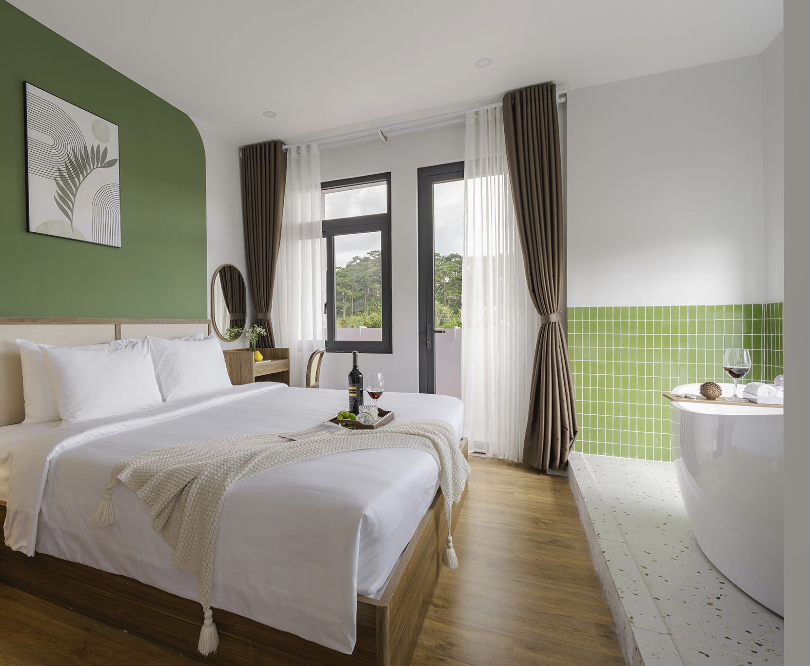 Una camera d'albergo con un letto matrimoniale, un comodino con una bottiglia e un bicchiere, una finestra con tende e un muro rivestito di piastrelle verdi.