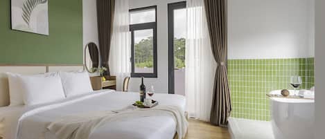 A hotel room with a double bed, a bedside table with a bottle and glass, a window with curtains, and a green-tiled wall.
