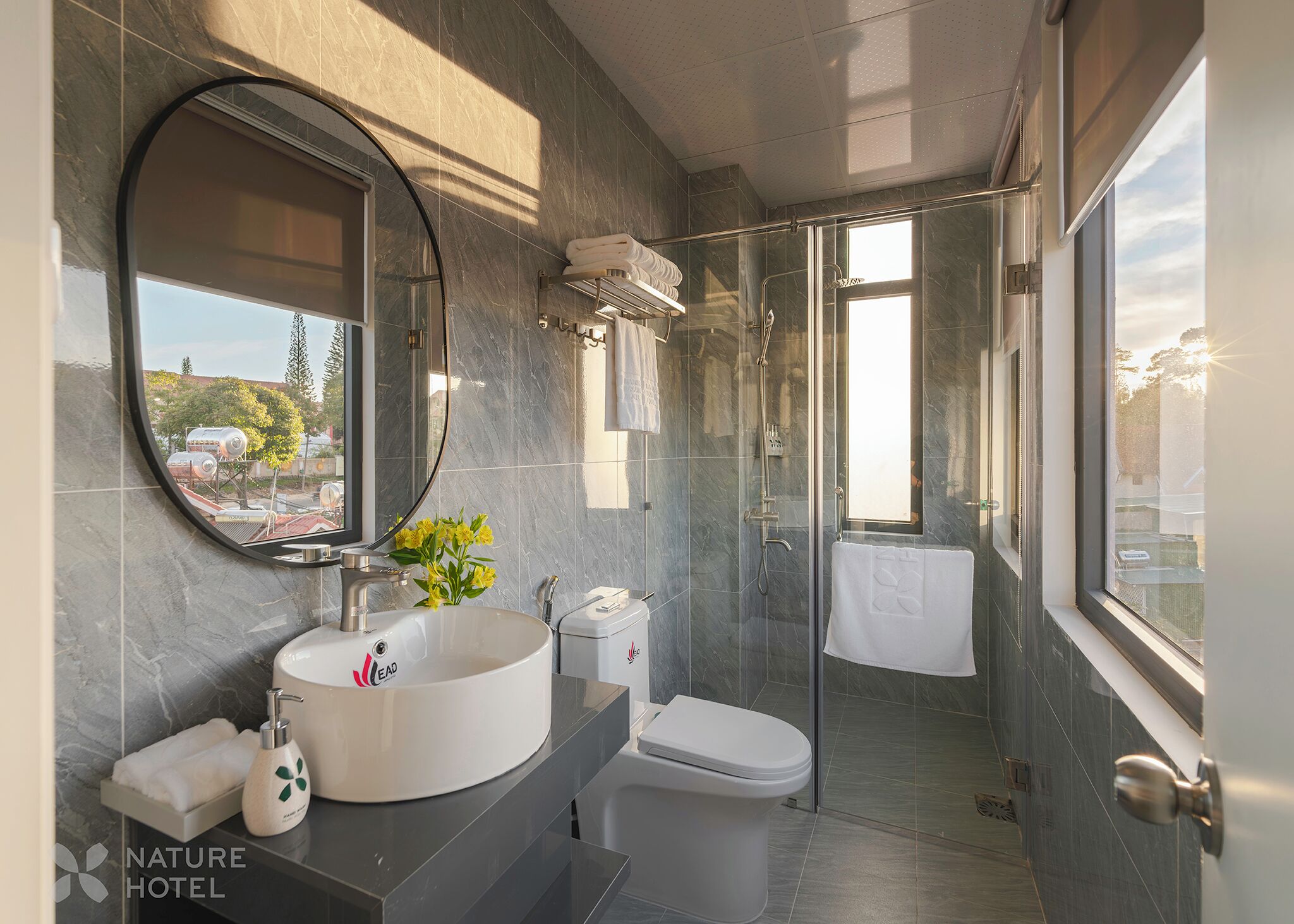 Un baño moderno con un espejo redondo, un lavabo, un inodoro y una zona de ducha.