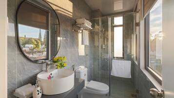 Un baño moderno con un espejo redondo, un lavabo, un inodoro y una zona de ducha.
