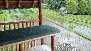 A wooden bench overlooking terraced rice fields with a thatched roof structure in the background.