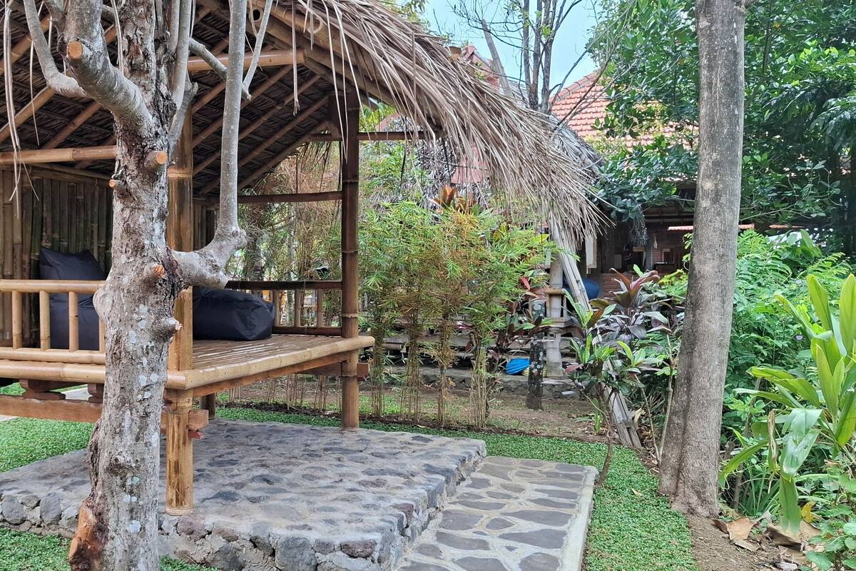 A wooden structure with a thatched roof, a bench, and a stone platform.