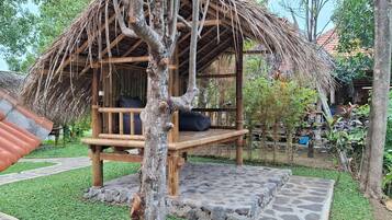 A wooden structure with a thatched roof, a bench, and a stone platform.