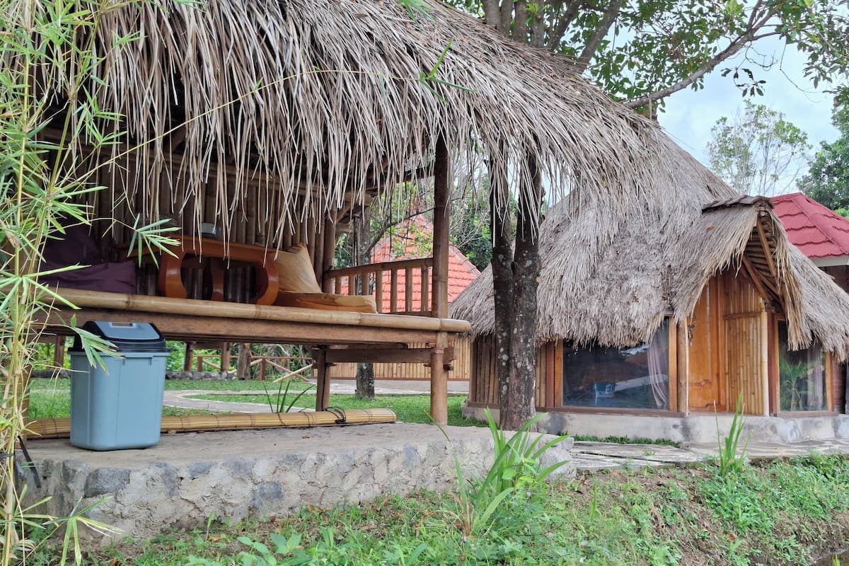 A traditional thatched-roof house with a wooden porch and a stone pathway leading to it.