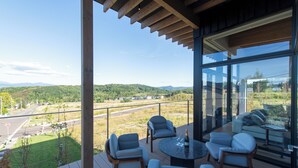 A modern outdoor deck with a panoramic view of a green landscape and distant buildings. - Shiyuki (Furano)