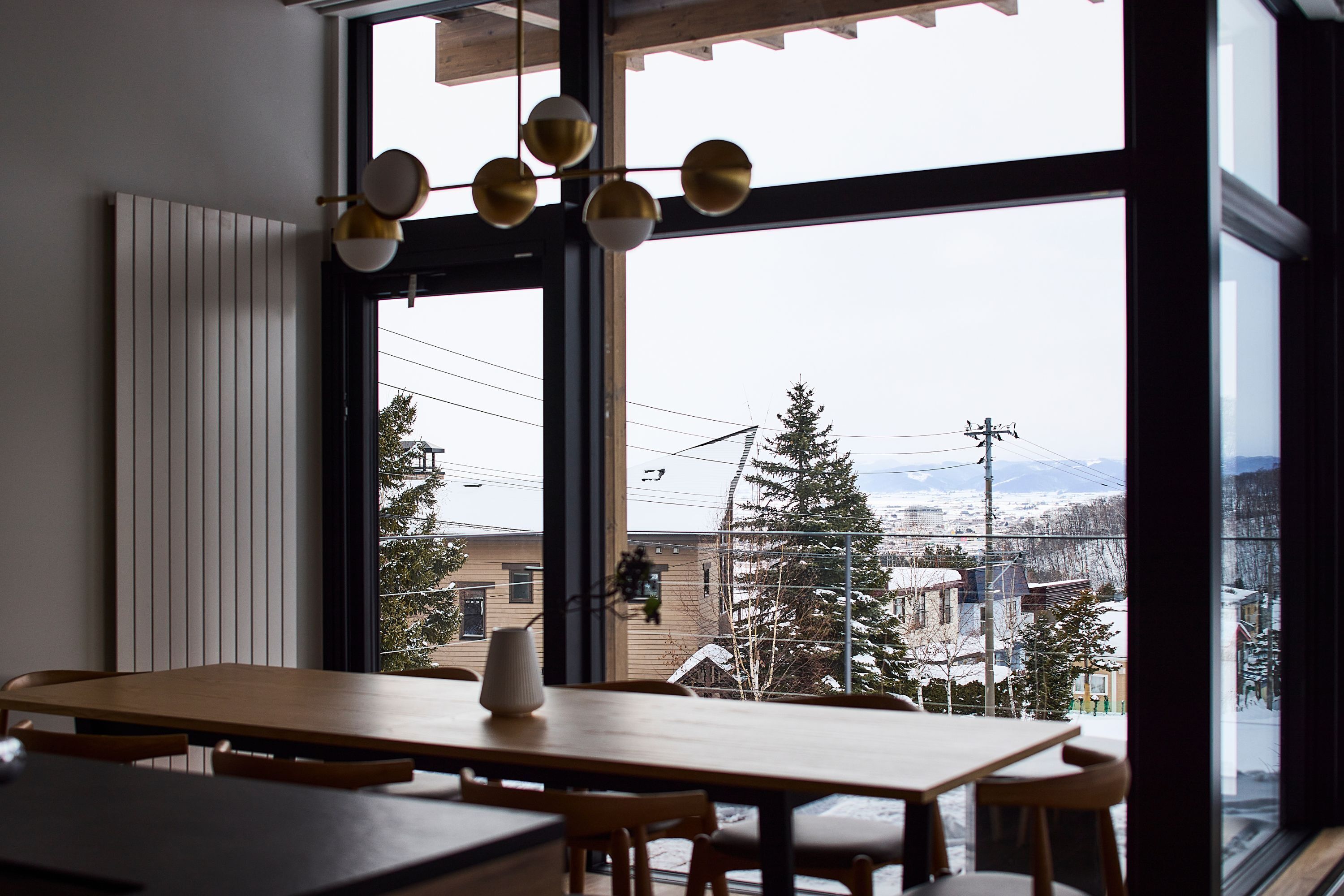 A dining area with a large window, wooden table, and chairs.