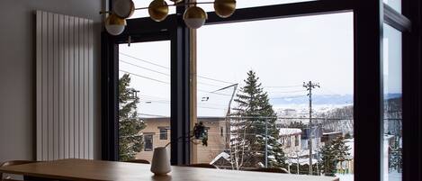 A dining area with a large window, wooden table, and chairs.