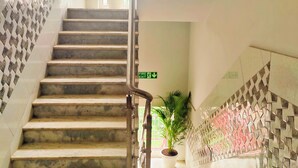 A staircase with a fire exit sign, potted plants, and patterned walls. - The Nook (Bhubaneshwar)