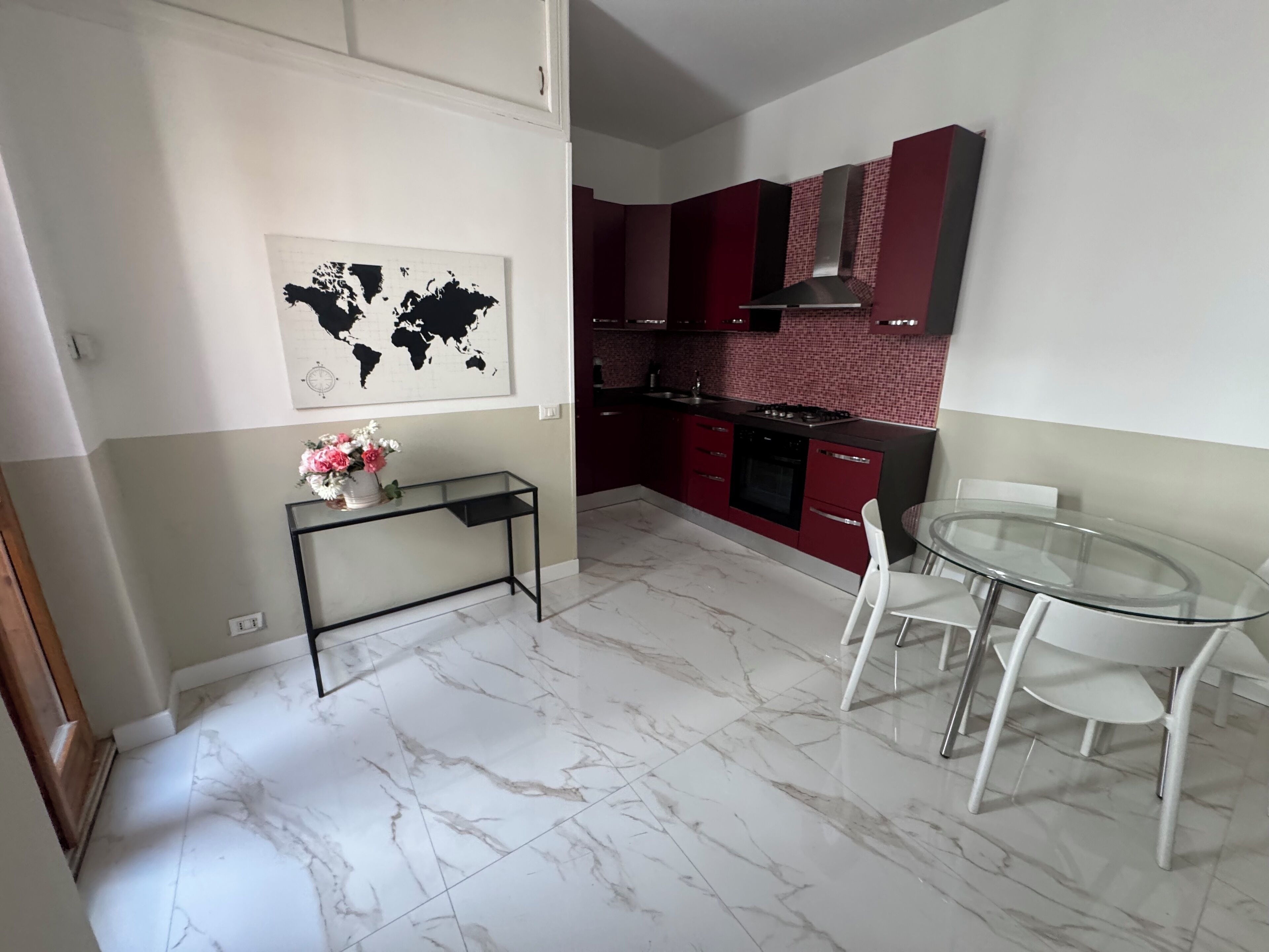 Una cucina moderna con mobili rossi, un piano cottura a gas e una mappa del mondo appesa al muro.