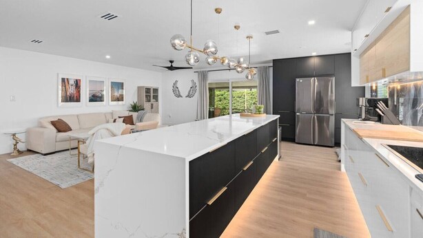 A modern kitchen with a central island, stainless steel appliances, and a dining area with a sofa.