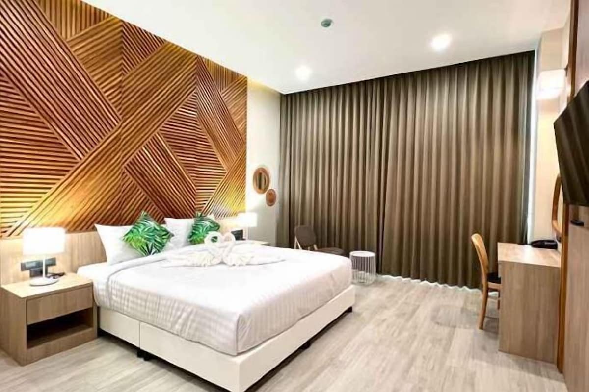 Une chambre à coucher moderne, équipée d’un lit, de tables de chevet, d’un bureau et d’un téléviseur.