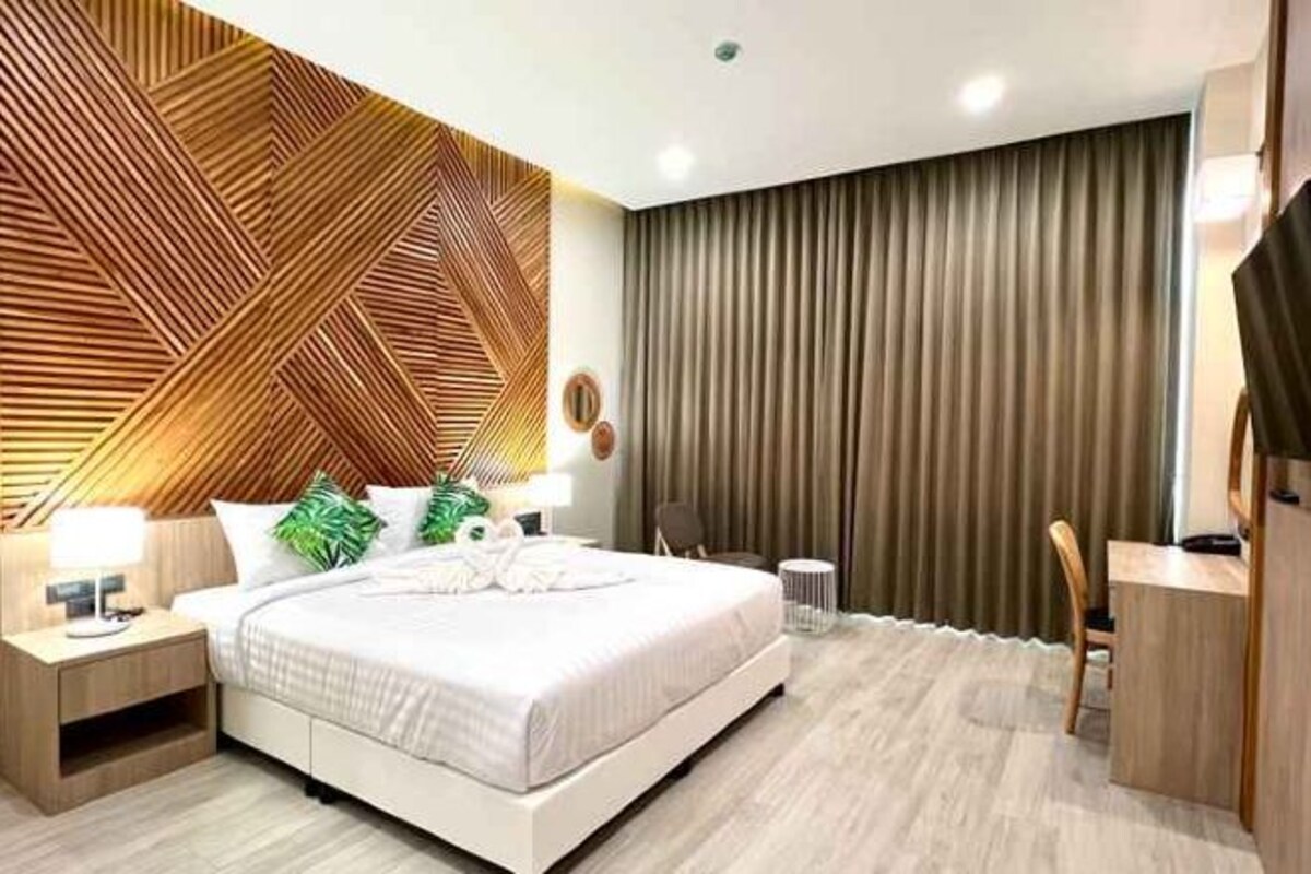A modern bedroom with a bed, bedside tables, a desk, and a television.