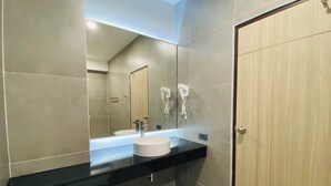 Een moderne badkamer met een grote spiegel, een zwart aanrecht, een wit wastafelmeubel en een houten deur.