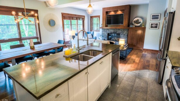 A modern kitchen with a large island, built-in appliances, and a stone fireplace.
