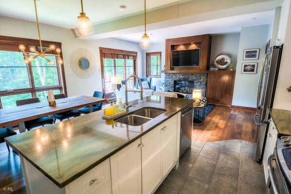 Una cocina moderna con una isla grande, electrodomésticos integrados y una chimenea de piedra.