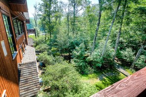 Ein Holzhaus mit einem Balkon, der auf einen dichten Wald blickt.