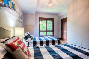 Ein Schlafzimmer mit zwei Betten, einem Fenster mit Blick auf Grünflächen und einer Chandelüster.