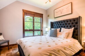 Un dormitorio con una cama grande, una ventana con persianas, un cuadro en la pared y una silla.