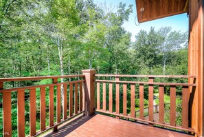 A wooden deck with a railing, surrounded by lush greenery.