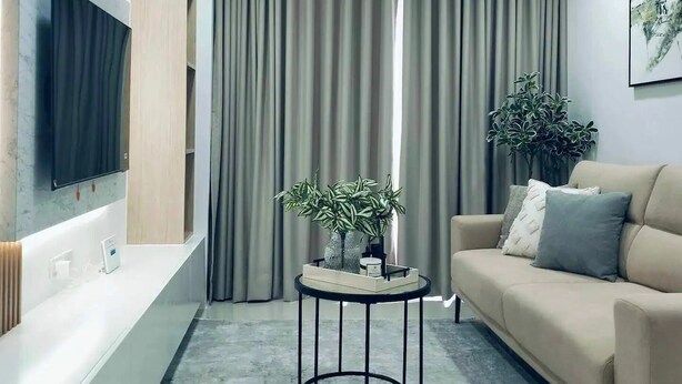 A modern living room with a sofa, a coffee table, a TV mounted on the wall, and a large window with curtains. - Stay in Unit 301 Pontefino Tower, a Cozy 1 Bedroom Apartment that is Brand New (Batangas)