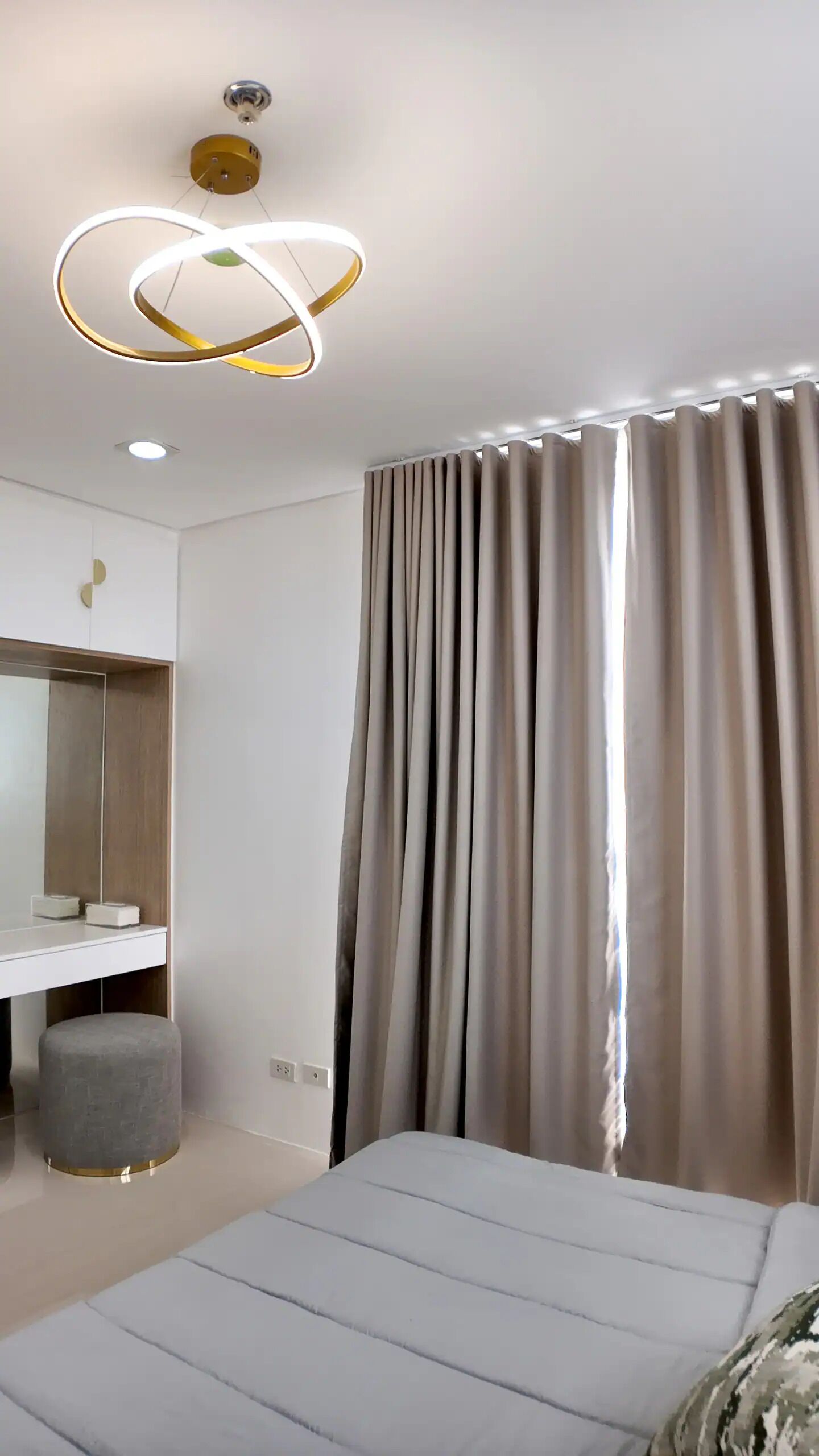 Un dormitorio moderno con cama, tocador con espejo y lámpara en el techo.
