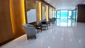 A modern hotel lobby with a clean, tiled floor and a row of grey armchairs along the wall. - Stay in Unit 301 Pontefino Tower, a Cozy 1 Bedroom Apartment that is Brand New (Batangas)