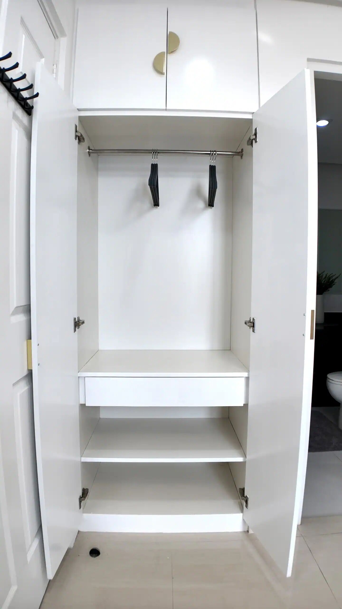 A white wardrobe with a hanging rod and a shelf.
