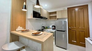 A modern kitchen with a central island, wooden cabinets, a stainless steel refrigerator, and pendant lighting. - Stay in Unit 301 Pontefino Tower, a Cozy 1 Bedroom Apartment that is Brand New (Batangas)