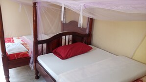 A single bed with a wooden frame and a canopy, a red pillow, and a white bedspread. - Kibale Eco Home  (Kibale)