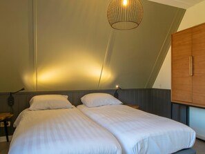 Een slaapkamer met twee bedden, een houten garderobe en een bijzondere plafondlamp.