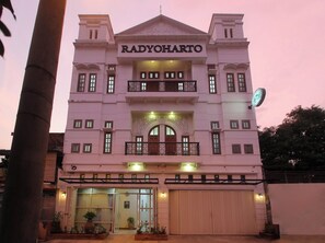 Un edificio con el nombre RADYOHARTO bien visible. Presenta una fachada simétrica con una entrada central, balcones y un reloj a la derecha.
