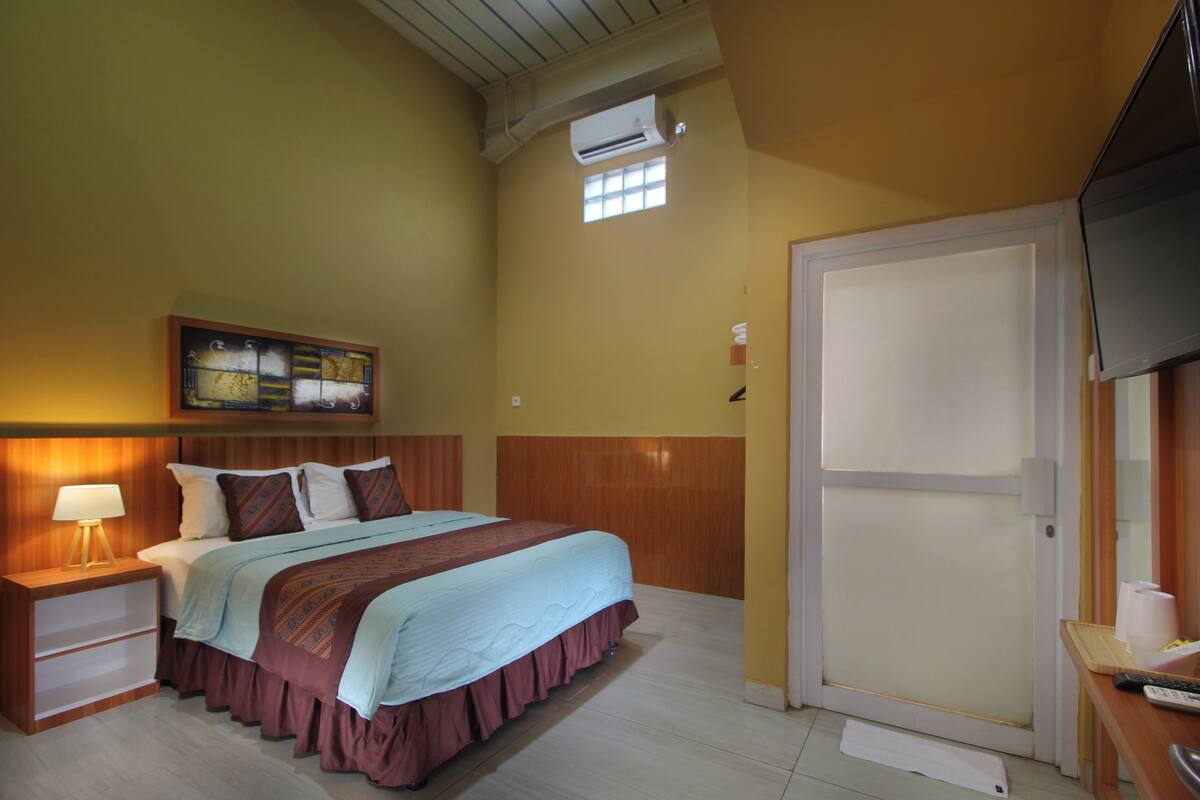 A bedroom with a bed, nightstand, and wall-mounted air conditioning unit.