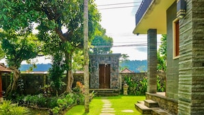 Un edificio de piedra con puerta de madera, rodeado de exuberante follaje y un camino de piedra que conduce a la entrada.
