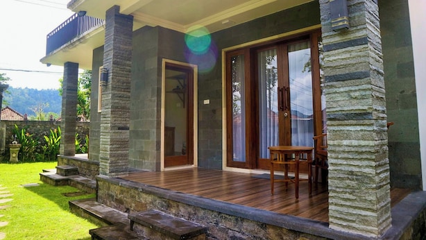 Una casa con terraza de madera, pilares de piedra y balcón.