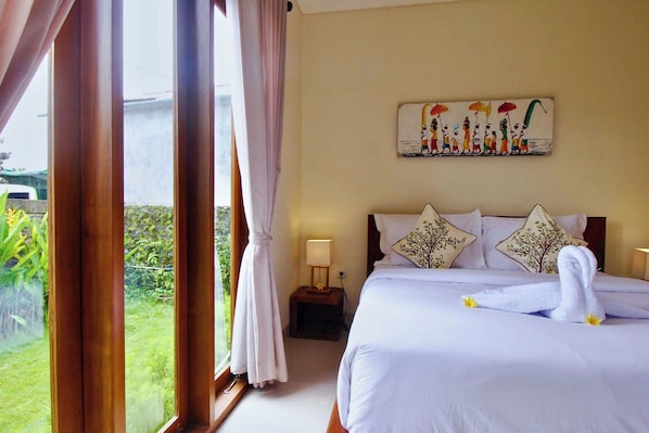 Una camera d'albergo con un letto, un comodino, un quadro e vista su vegetazione.