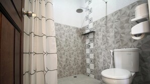 Un baño con ducha, inodoro y pared con diseño.