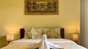 Una habitación de hotel con una cama grande, dos almohadas estampadas y un cuadro en la pared.