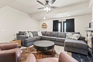Una sala moderna con un sofá modular, una mesa de centro redonda y un ventilador de techo.