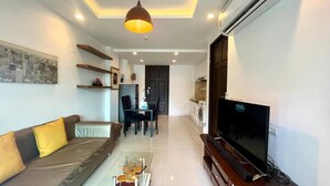 Una sala de estar moderna con sofá, mesa de centro, televisor y zona de cocina.