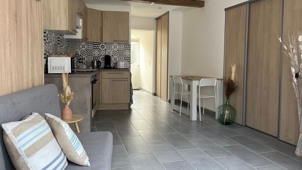 Una cocina moderna con armarios de madera, salpicadero con diseño y una zona de comedor con mesa y sillas.