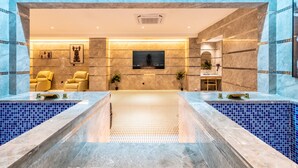 A modern spa area with a large central pool, seating area with yellow chairs, and a television on the wall. - Bole Boutique Hotel, Sihanoukville (Sihanoukville)