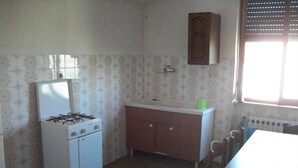 Una pequeña cocina con estufa a gas, un lavamanos y un armario.