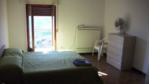 Un dormitorio con cama, radiador, silla y cómoda.