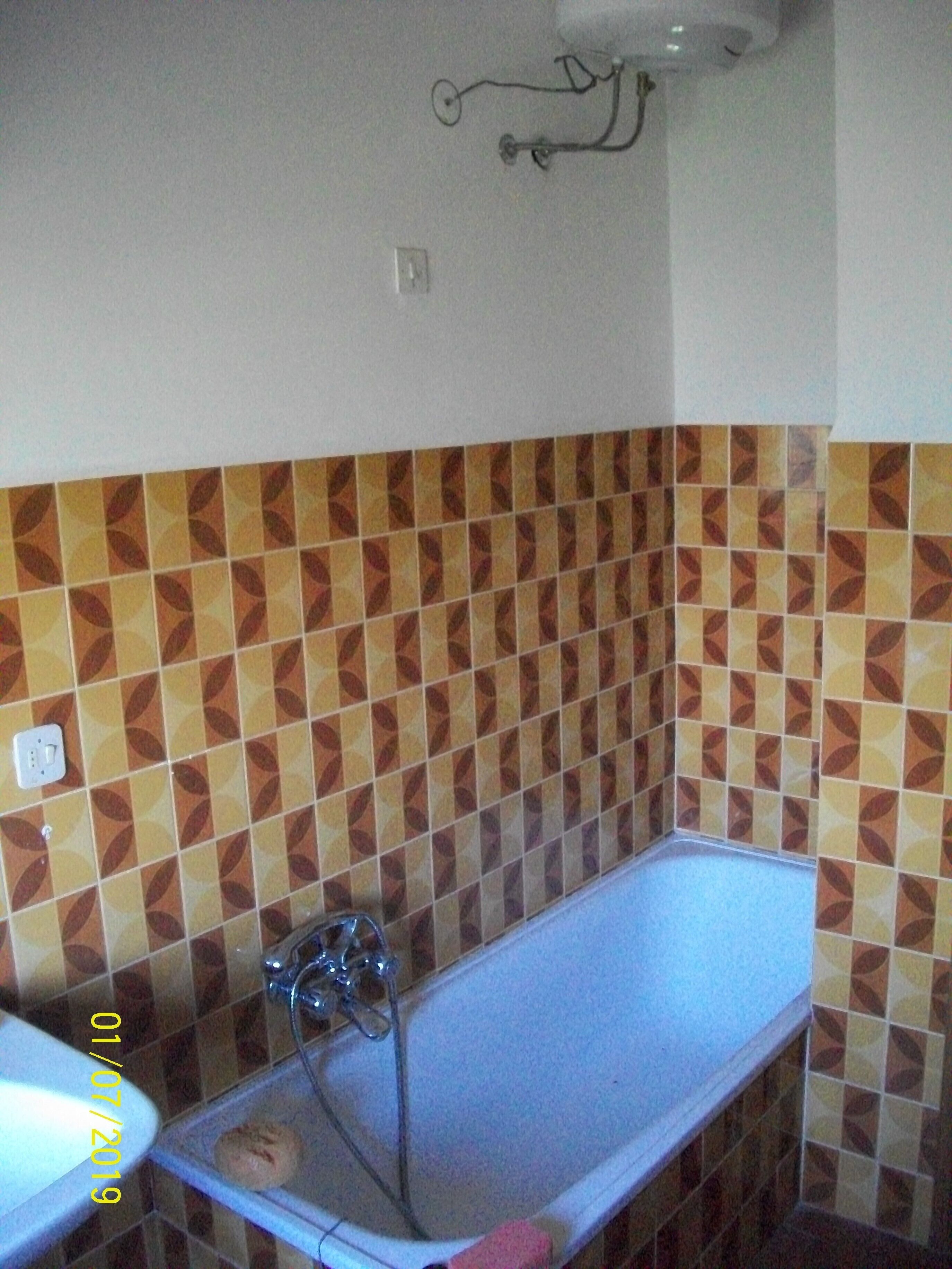 Ein Badezimmer mit einer Badewanne, einem Waschbecken und einer Wand mit gemusterten Fliesen.